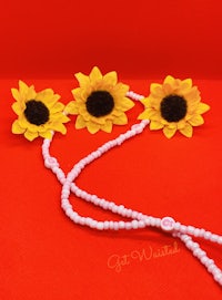 a necklace with sunflowers and beads on a red background